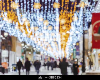 Weihnachtlich dekorierte Straße. Verschneite Winterstraße mit Leuten. Weihnachten und frohes neues Jahr, verschwommenes Bokeh. Authentische Aufnahme von farbenfrohem christm Stockfoto