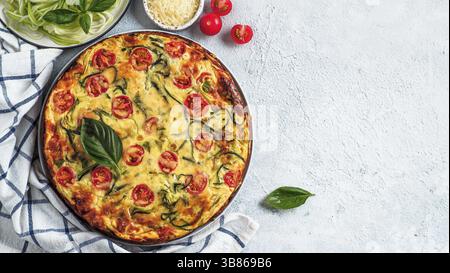 Zucchini Pie auf grauem Hintergrund, kopieren Raum rechts. Draufsicht auf köstliche herzhafte Kuchen mit Zucchini, Tomaten, Kräutern und Käse. Idee und Rezept für hea Stockfoto