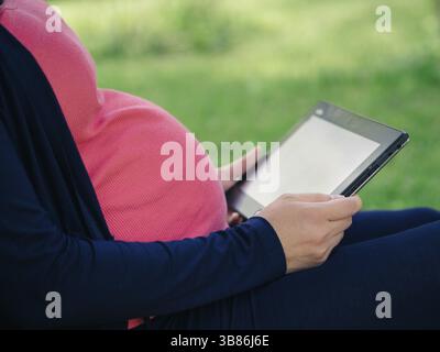 Schwangere Frau mit Tablet-E-Reader Stockfoto