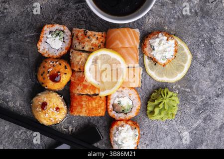 Sushi-Brötchen, serviert am grauen Tisch. Flache Lagen. Nahaufnahme Stockfoto