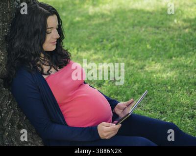 Schwangere Frau mit Tablet-E-Reader Stockfoto