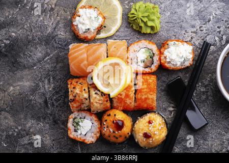 Sushi-Brötchen, serviert am grauen Tisch. Flache Lagen. Nahaufnahme Stockfoto