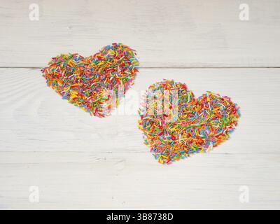 Süßigkeiten Formen Herzform. Bunte Herzform aus Süßigkeiten-Konfetti auf weißem Holzhintergrund. Valentinstag-Konzept. Kopierraum Stockfoto
