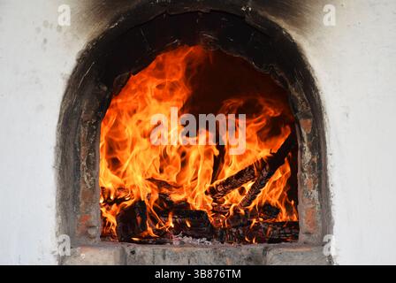 Nahaufnahme eines tosenden Feuers in einem rustikalen Backofen mit brennendem Brennholz und lebhaften orangen Flammen. Visuell von Wärme und Energie. Konzept. Stockfoto