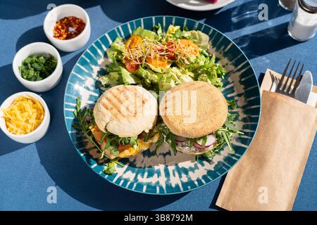 Ein Brötchen Rührei und weißer Hüttenkäse serviert mit Gemüse und Gemüse auf einem wunderschön dekorierten Teller, ein Frühstücksset Stockfoto