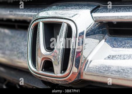 Nahaufnahme des Honda-Logos auf einem mit Regentropfen bedeckten Fahrzeug. Stockfoto