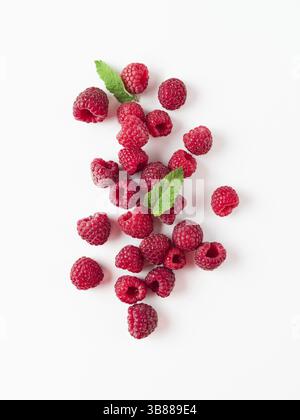 Haufen frischen reifen roten Himbeeren mit grünen Blättern auf weißem Hintergrund. Top View oder flach. Vertikale Stockfoto