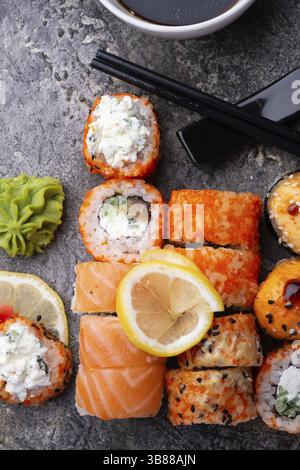 Sushi-Brötchen, serviert am grauen Tisch. Flache Lagen. Nahaufnahme Stockfoto