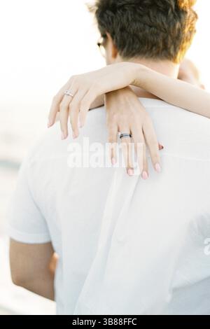 Frauenhände umarmen einen Mann am Hals. Nahaufnahme. Rückansicht. Stockfoto