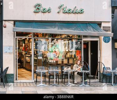 London, England - 28. April 2025: Eine Frau genießt ihren Morgenkaffee vor der Bar Italia, einem bekannten italienischen Café, das 1949 in der Frith Street in eröffnet wurde Stockfoto