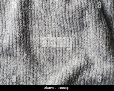 Graue Strickjacke Stoff Textur. Kleidung Pullover Hintergrund mit Falten Stockfoto