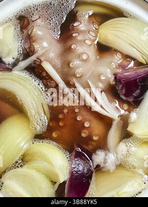 Oktopustentakel mit Zwiebelstücken kochen in einem Topf. Stockfoto