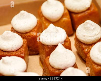 Mini-Rum-Babas mit zarten Baisons, serviert als elegante Nachspeisen im Beißformat an einem festlichen Buffet oder einer festlichen Feier. Stockfoto