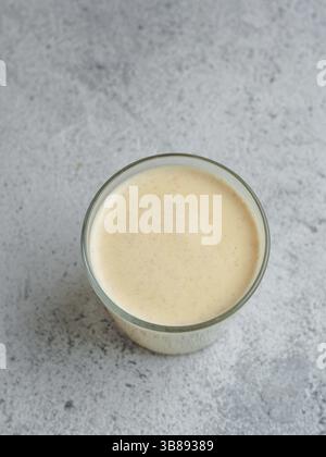 Gesundes Getränk goldene Kurkuma Latte in Glas Tasse. Gelber hausgemachter Latte auf grauem Hintergrund. Detox Kurkuma Tee Latte. Copyspace für Text Draufsicht oder f Stockfoto