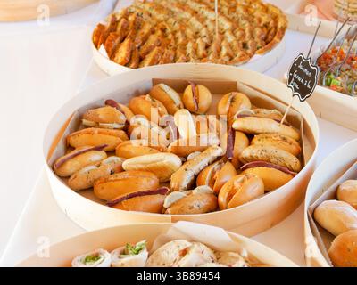 Mini-Wurst-Sandwiches, serviert auf weichen Brötchen für ein Hochzeitsbuffet, ideal für einen eleganten und herzhaften Cocktail-Empfang. Stockfoto