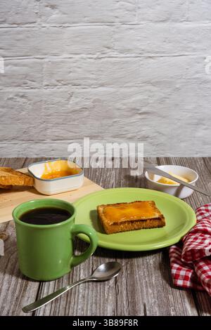 Genießen Sie ein einfaches, aber reichhaltiges Frühstück mit Kaffee, Toast mit Marmelade und Butter, serviert auf einem rustikalen Holztisch Stockfoto