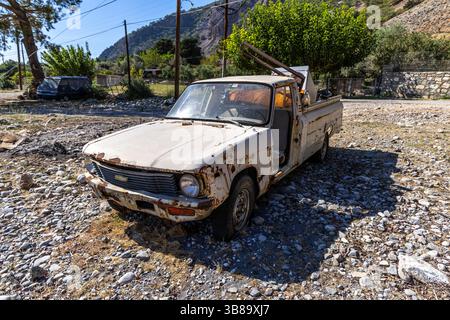 Kreta, Griechenland - 18. Oktober 2024: Ein alter, verrosteter LKW, der am Ende der Samaria-Schlucht geparkt wurde, mit einem weggeworfenen Gerät hinten, gegen einen Rücken gestellt Stockfoto