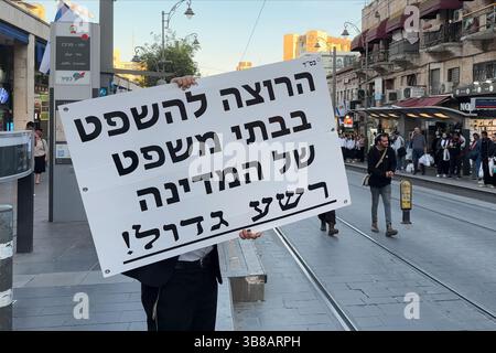 Ein ultra-orthodoxer religiöser Jude hält ein Schild mit der Aufschrift: "Jeder, der einen Prozess vor einem Gericht sucht, ist ein großer Übeltäter." Als er am 7. Mai 2025 in Jerusalem jüdisches Recht auf der Grundlage der Tora-Alternative zum säkularen Rechtssystem des Staates fördert. Israel Stockfoto