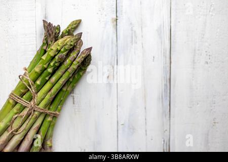 Ein Bündel frischer Spargel. Eine Nahaufnahme zeigt ein Bündel frischer, grüner Spargelstangen, die mit Garn verbunden sind. Stockfoto