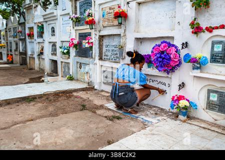 Eine Kolumbianerin repariert die Inschrift im Kolumbarium vor den Feierlichkeiten der Karwoche auf dem Friedhof in Mompox, Kolumbien. Stockfoto