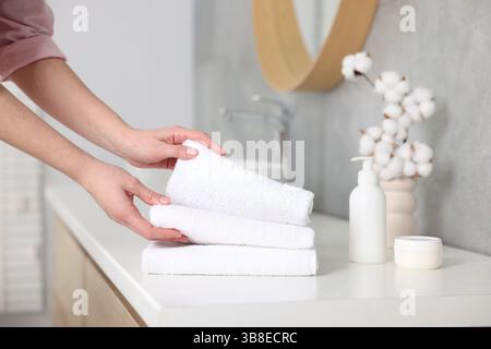 Frau, die saubere Handtücher vom Waschtisch im Bad nahm, Nahaufnahme Stockfoto