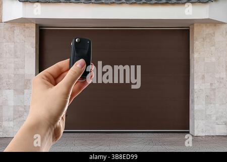 Frau, die die Garagentür draußen mit Fernbedienung steuert, Nahaufnahme Stockfoto