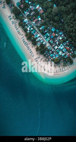 Luftdrohnenaufnahme der Stadt am Rand des tiefblauen Wassers und des weißen Sandufers. Stockfoto