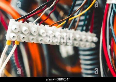 Nahaufnahme des elektrischen Anschlussklemmenblocks mit farbigen Drähten, die in einem Industrietafel angeschlossen sind Stockfoto