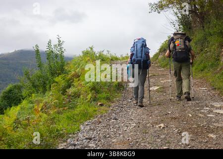 Zwei unbekannte Pilger auf dem Jakobsweg. Zwei Wandertouristen mit Rucksäcken in den Bergen. Pilgerkonzept. Konzept für aktive Personen. Stockfoto