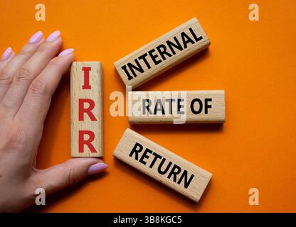 IRR - Internal Rate of Return symbol. Concept word IRR on wooden cubes. Businessman hand. Beautiful orange background. Business and IRR concept. Copy Stockfoto