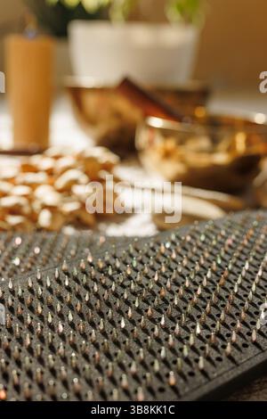 Nahaufnahme des Sadhu-Meditations-Nagelbretts im warmen Licht auf dem Boden zu Hause mit Klangschalen und Meditationsinstrumenten Stockfoto