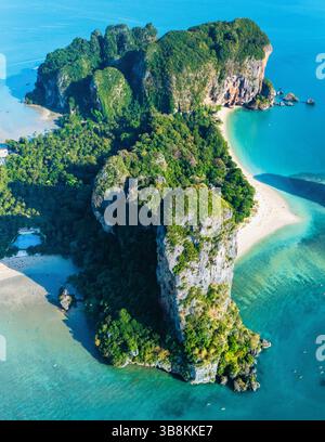 Bestaunen Sie die atemberaubende Landschaft von Railay Beach, wo üppige grüne Klippen auf türkisfarbenes Wasser treffen. Besucher können die ruhige Schönheit dieses tropischen Paradieses in Krabi, Thailand, genießen. Stockfoto