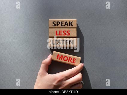 Weniger sagen, mehr hören. Holzblöcke mit Wörtern sprechen weniger Hören Sie mehr. Schöner grauer Hintergrund. Geschäftsmann Hand. Geschäftlich und sprich weniger L Stockfoto