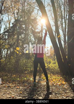 Waldweg im Herbst. Herbstläuferin, die in wunderschönen Laubwäldern läuft, Natur Hintergrund. Asiatische glückliche Sportfrau, die im Freien trainiert. . Hg Stockfoto