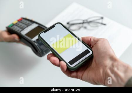 Hände, die POS-Terminal und Smartphone verwenden, um nfc-Zahlungen durchzuführen, financinal Operation. Optionen für Massenzahlungen und Konzept für Geschäftsabläufe Stockfoto