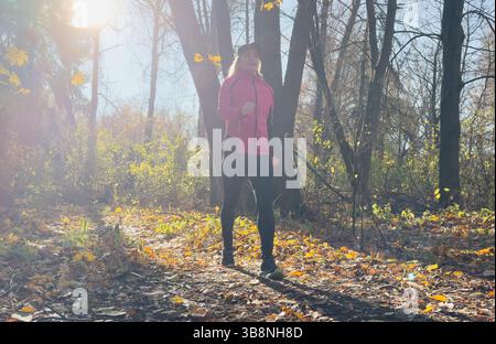 Waldweg im Herbst. Herbstläuferin, die in wunderschönen Laubwäldern läuft, Natur Hintergrund. Asiatische glückliche Sportfrau, die im Freien trainiert. . Hg Stockfoto