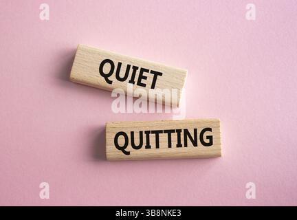 Symbol für leises Beenden. Konzeptwort leises Verlassen auf Holzblöcken. Schöner rosafarbener Hintergrund. Business- und ruhiges Reisekonzept. Kopierbereich. Stockfoto