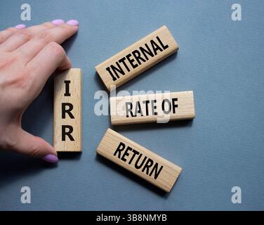 IRR - Internal Rate of Return symbol. Concept word IRR on wooden cubes. Businessman hand. Beautiful grey background. Business and IRR concept. Copy sp Stockfoto