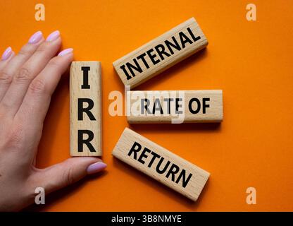 IRR - Internal Rate of Return symbol. Concept word IRR on wooden cubes. Businessman hand. Beautiful orange background. Business and IRR concept. Copy Stockfoto