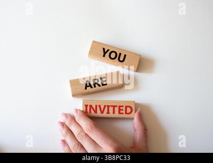 Symbol „Sie sind eingeladen“. Holzblöcke mit Worten, die Sie eingeladen sind. Schöner weißer Hintergrund. Geschäftsmann Hand. Business und Sie sind eingeladen Konzept. Stockfoto