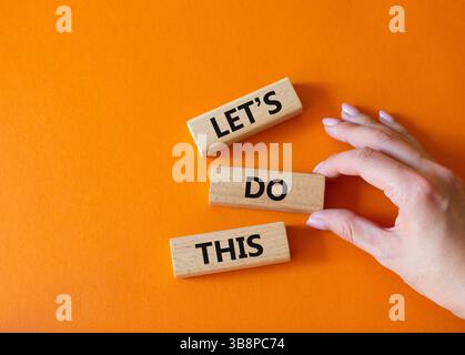 Machen wir dieses Symbol. Konzeptwort Lassen Sie uns das auf Holzblöcken machen. Geschäftsmann Hand. Wunderschöner orangefarbener Hintergrund. Und machen wir dieses Konzept. Stockfoto