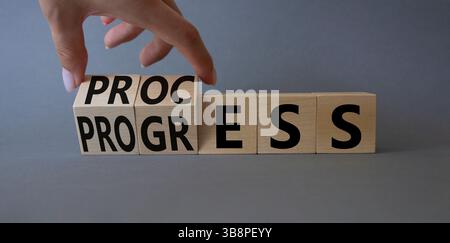 Symbol für Prozess und Fortschritt. Die Hand dreht Holzwürfel und ändert den Wortfortschritt in „Prozess“. Schöner grauer Hintergrund. Business und Prozesse und Programme Stockfoto