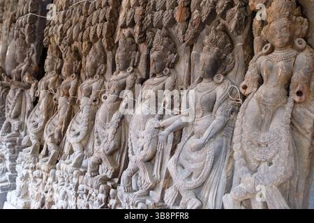 Antike Steinschnitzereien himmlischer Tänzer oder Apsaras zieren eine Tempelmauer und zeigen traditionelle Kunst und Hingabe. Stockfoto