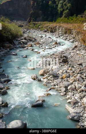 Gletscherschmelzwasser fließt durch ein felsiges Flussbett, das einen Pfad durch die Berge zieht. Das türkisfarbene Wasser ist kalt und flink. Stockfoto