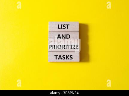 Symbol Aufgaben auflisten und priorisieren. Konzeptwörter Listen Sie Aufgaben auf Holzblöcken auf und priorisieren Sie sie. Schöner gelber Hintergrund. Geschäft und Liste und Priorität Stockfoto
