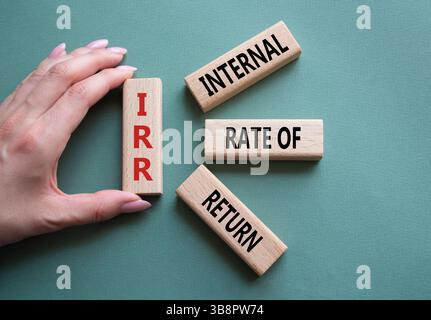 IRR - Internal Rate of Return symbol. Concept word IRR on wooden cubes. Businessman hand. Beautiful grey green background. Business and IRR concept. C Stockfoto