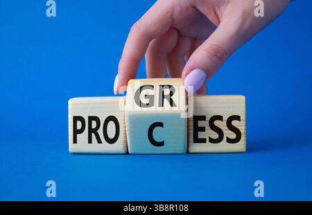 Symbol für Prozess und Fortschritt. Die Hand des Geschäftsmannes dreht Holzwürfel und ändert das Wort Prozess und Fortschritt. Wunderschöner blauer Hintergrund. Business und PR Stockfoto