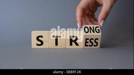 Symbol für starke Spannung. Die Hand des Geschäftsmannes verwandelt Holzwürfel und ändert Wortspannung in stark. Schöner grauer Hintergrund. Geschäftliche und starke Stressbelastung Stockfoto