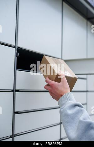 Nahaufnahme eines Mannes, der einen Karton aus einem automatisierten Paketschließfach platziert oder abgeholt hat Stockfoto