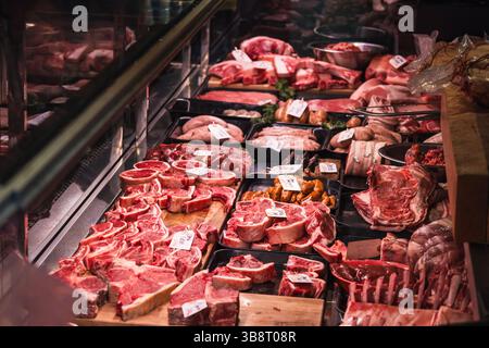Frisches Fleisch wird im lebhaften Metzgerstand auf dem Lebensmittelmarkt mit verschiedenen Optionen gezeigt Stockfoto